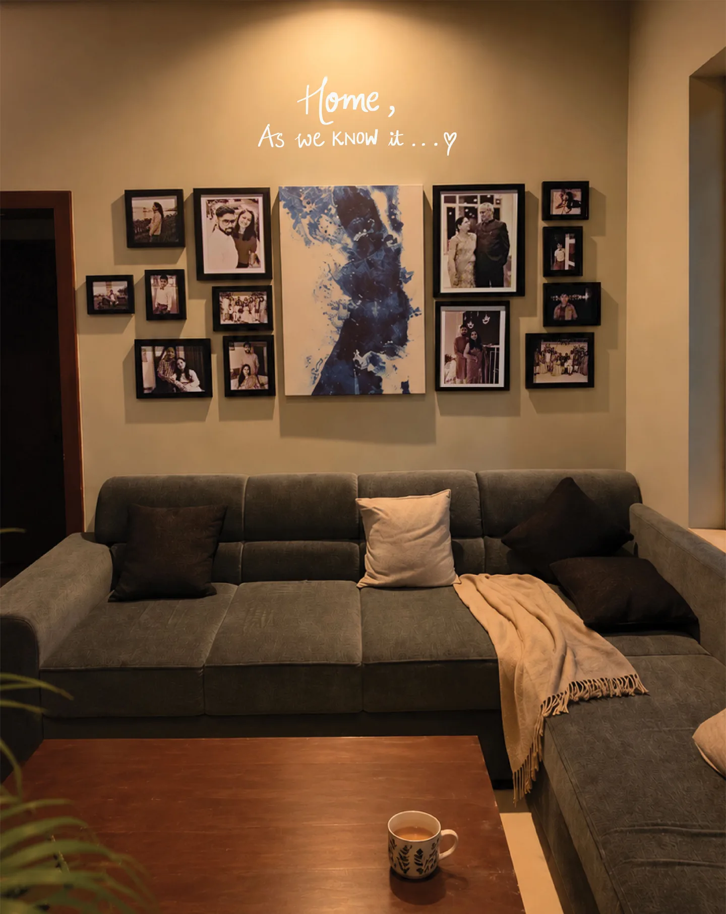 Home, as we know it. A living room wall full of family photographs, with a cup of chai on the table.